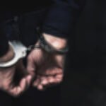 handcuffed arrested man behind prison bars. copy space